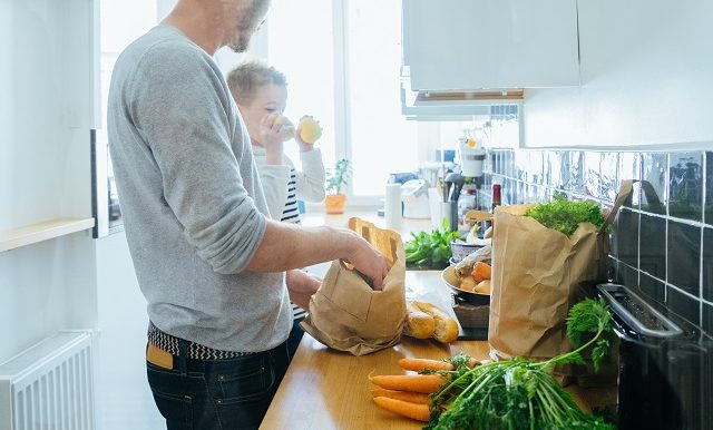 Un père et son fils vident des sacs d’épicerie dans la cuisine