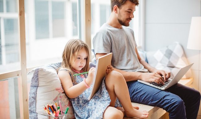 Un père travaille à côté de a fille qui dessine
