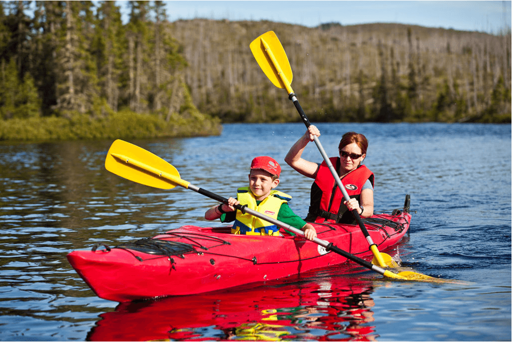 Un garçon et une femme qui pagaient dans un kayak rouge