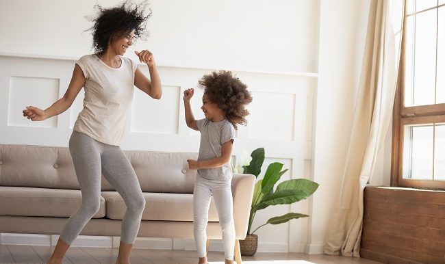une mère et sa fllle dansent dans le salon