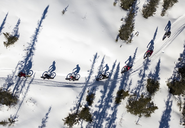 groupe de gens en fatbike dans un sentier enneigé