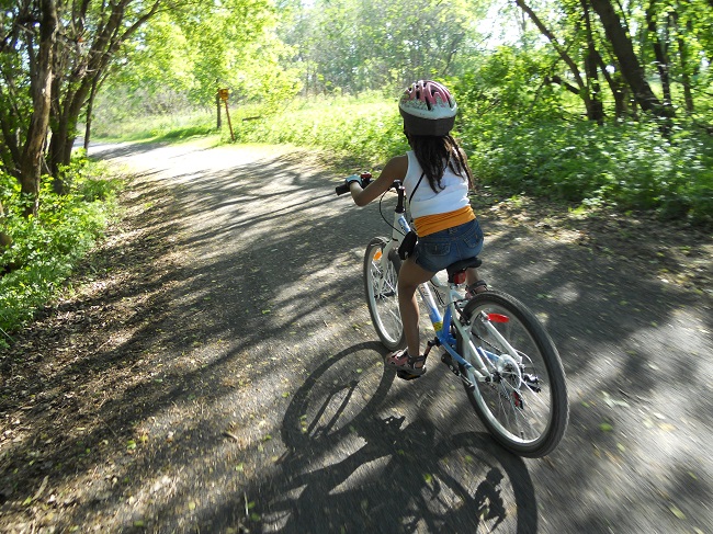 fillette qui pédale sur une piste cyclable en gravier sur l'ile de boucherville