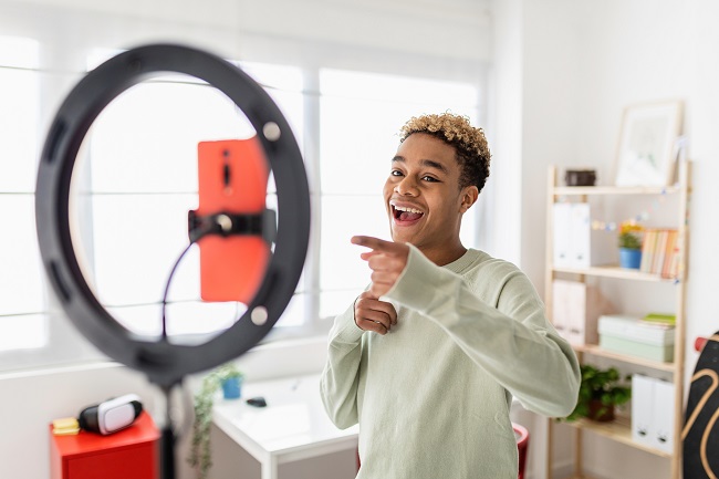 Jeune créateur masculin enregistrant une vidéo multimédia en ligne dans sa chambre