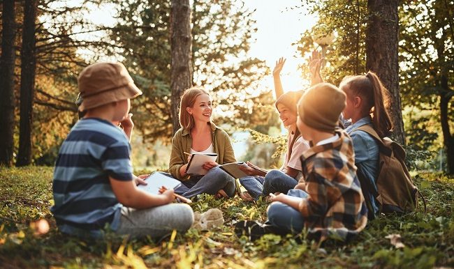 enseignante qui fait la classe a un groupe d'éleve en plain air