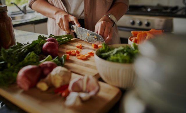 Mains féminines coupant des légumes sur une planche à découper