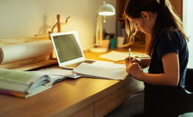 adolescente qui fait ses devoirs sur un bureau de travail