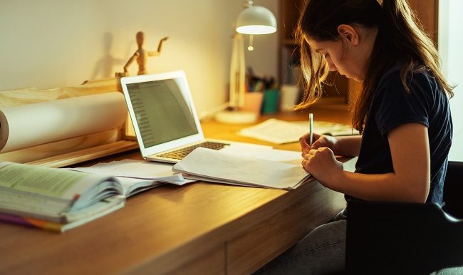 adolescente qui fait ses devoirs sur un bureau de travail