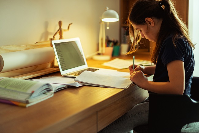 adolescente qui fait ses devoirs sur un bureau de travail