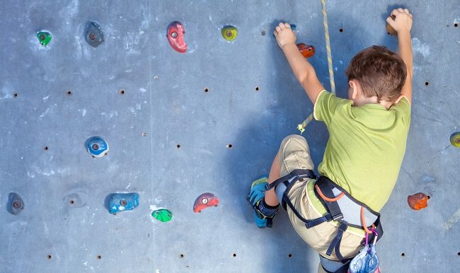 garcon qui grimpre a mur escalade intérieur