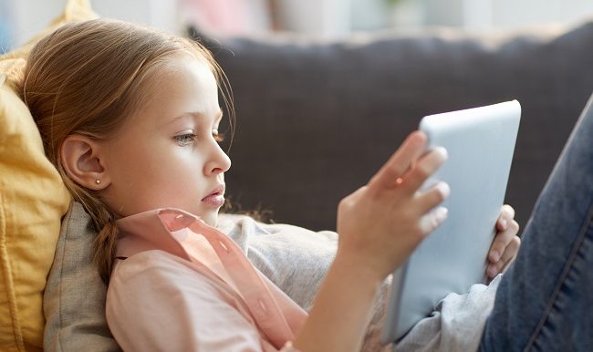 Jeune fille étendu sur le fauteul qui regarde une tablette