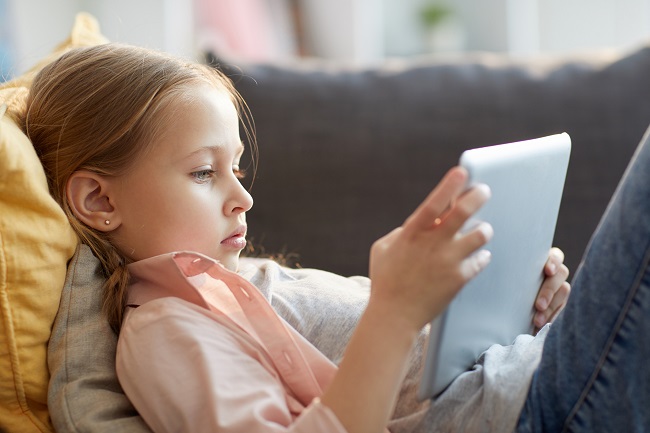 Jeune fille étendu sur le fauteul qui regarde une tablette