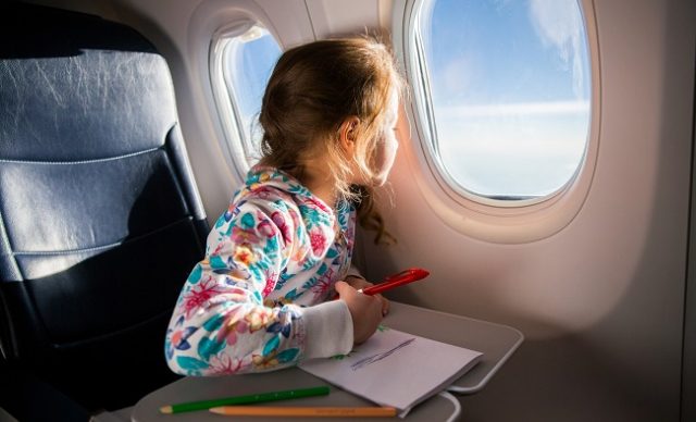 jeune fille qui regarde par le hublot d’un avion