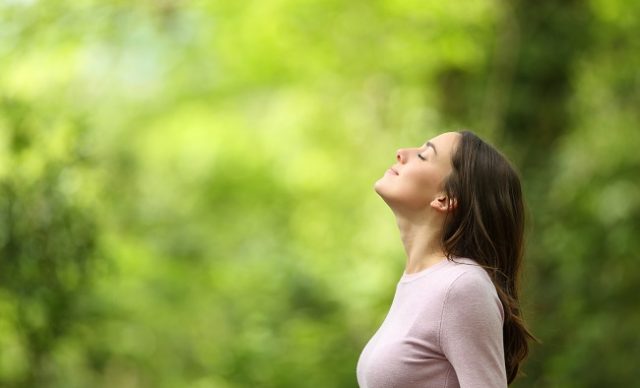 Femme respirant l’air frais dans une forêt verte