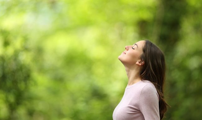 Femme respirant l’air frais dans une forêt verte
