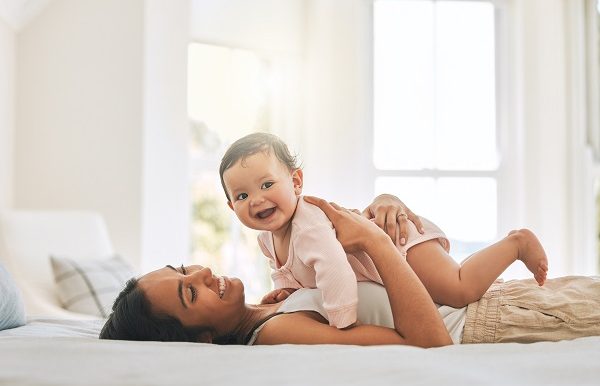 maman et bébé souriant couché sur le lit