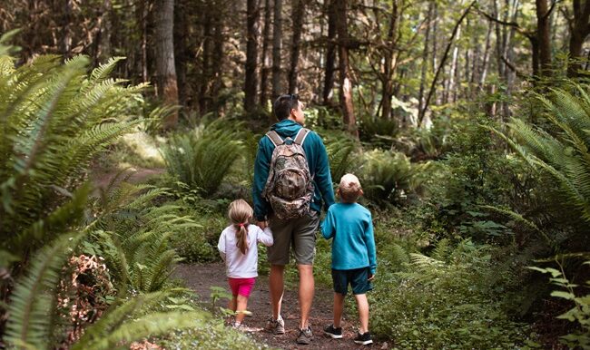 Father, son and daughter walking through a forest in Washington state.